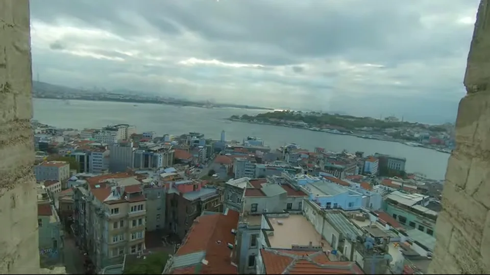Galata Tower rising above trees under a dramatic cloudy sky